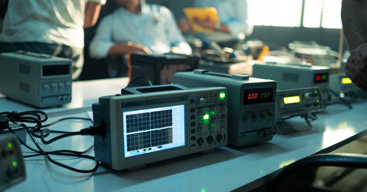 Engineers working in an electronics lab with oscilloscopes and other equipment on a bright day.